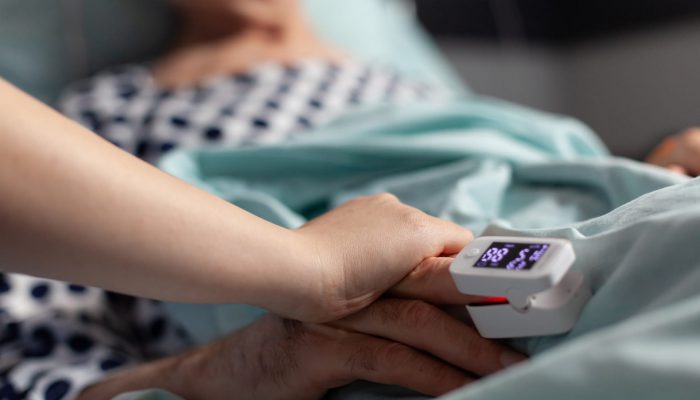 пульсоксиметр на пальце пожилой пациентки в кровати во время эпидемии коронавируса